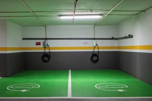 A parking garage with green and gray walls, yellow and gray stripes, and two electric vehicle charging stations. - BessaHotel Boavista (Porto)