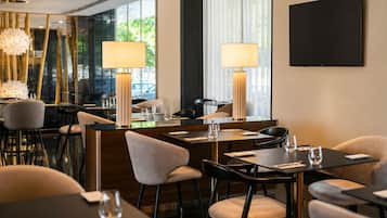 Un comedor moderno con mesas, sillas e iluminación ambiental.