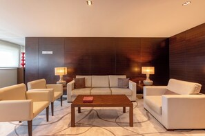 Un salon moderne comprenant un ensemble de canapés, deux tables d’appoint avec des lampes et une table basse en bois.