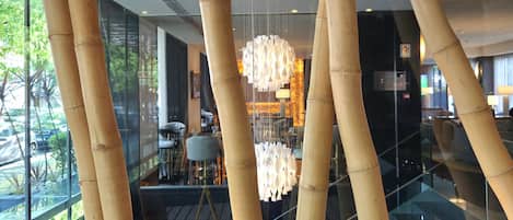 A modern interior with bamboo columns, a glass railing, and a central chandelier.