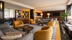 En modern hotellobby med en sittgrupp, en receptionsdisk och en bar.