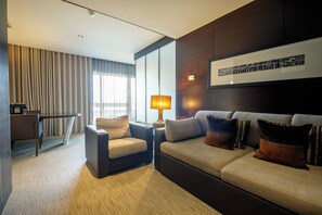 A modern hotel room with a sofa, armchair, and a dining table. - BessaHotel Boavista (Porto)