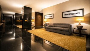 A modern hotel lobby with a sofa, a rug, framed pictures, and a lamp. - BessaHotel Boavista (Porto)