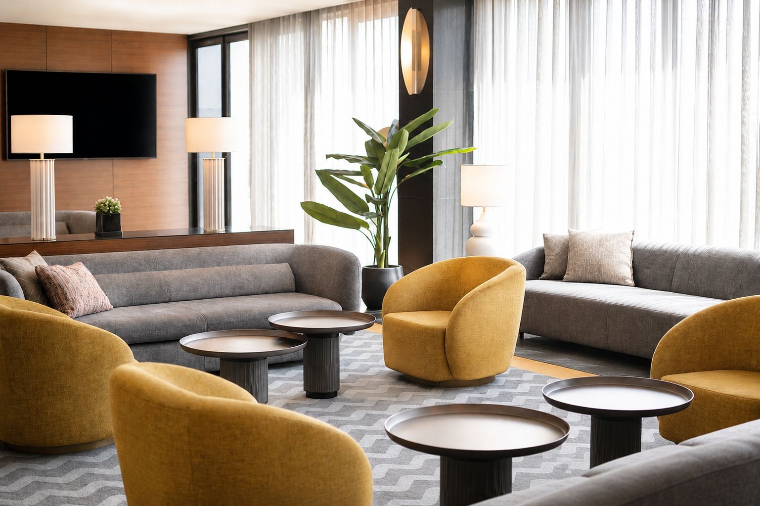 A modern living room with sofas, armchairs, and round tables, featuring a large plant and a flat-screen TV.