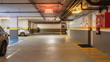 A hotel parking garage with clear signage for hotel access, a fire extinguisher mounted on the wall, and a fire hose reel.