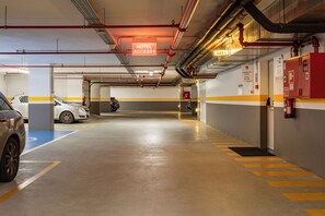 A hotel parking garage with clear signage for hotel access, a fire extinguisher mounted on the wall, and a fire hose reel. - BessaHotel Boavista (Porto)