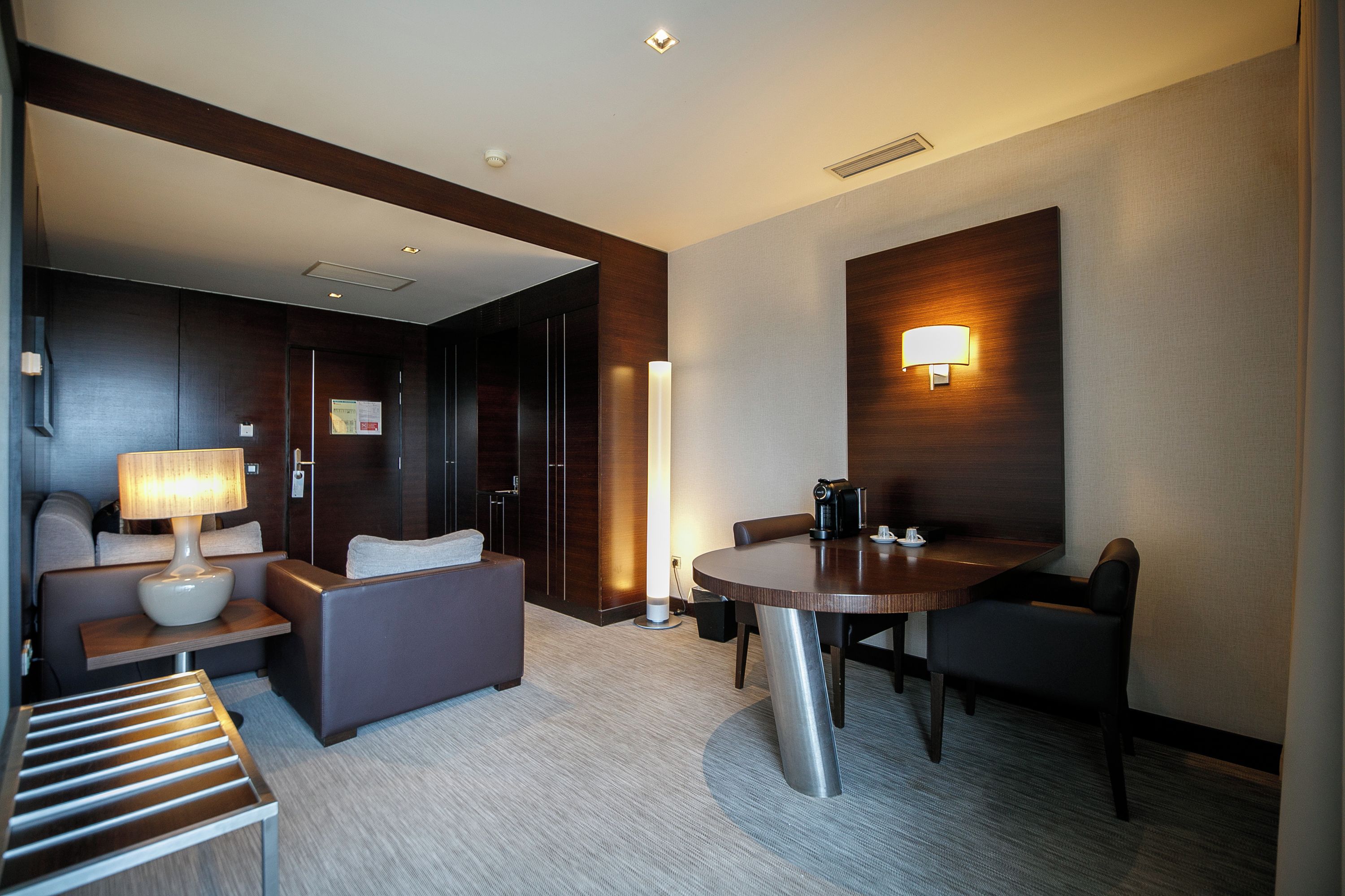 Quarto de hotel moderno com sofá, mesa e luminária.
