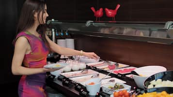 Montaje de bufé con diversos alimentos y una mujer sirviendo.