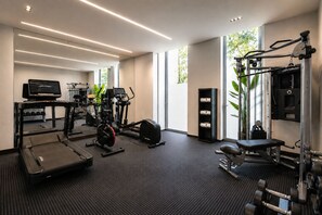 Une salle de sport moderne équipée de tapis de course, de vélos elliptiques et de matériel de musculation.