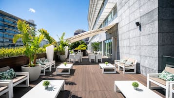 Una terraza en la azotea con mobiliario exterior, plantas en macetas y vistas panorámicas de la ciudad.