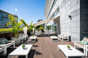 A rooftop terrace with outdoor seating, potted plants, and a view of the cityscape.