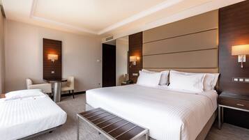 Una habitación de hotel con una cama grande, una cama más pequeña, un escritorio y dos sillas.