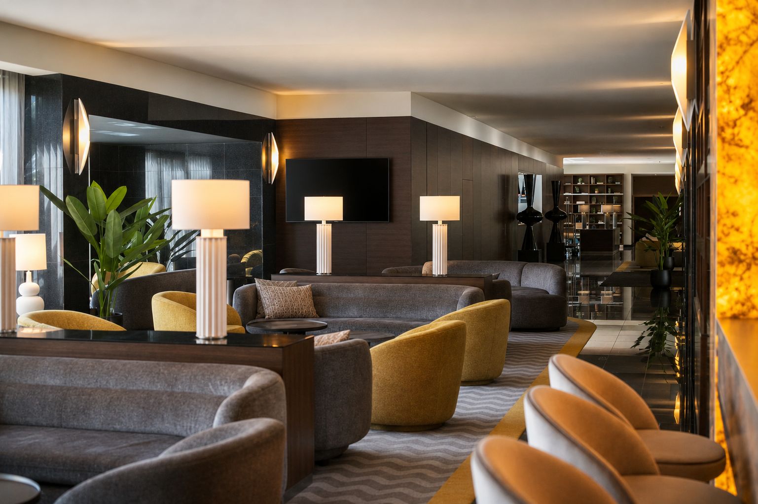 Un moderno hall de hotel con áreas de estar, lámparas y un televisor de pantalla plana grande.
