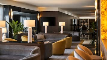 Un moderno hall de hotel con áreas de estar, lámparas y un televisor de pantalla plana grande.