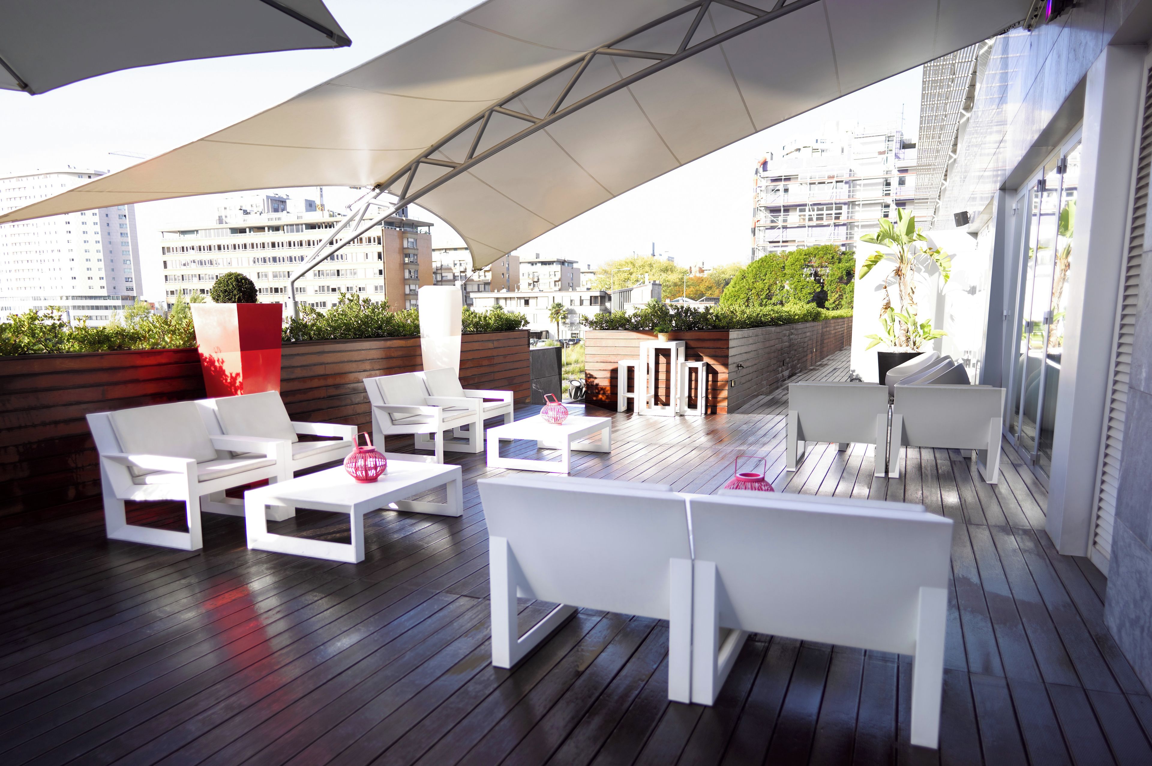 Terraza en la azotea con mobiliario blanco, una sombrilla grande y vistas a la ciudad.