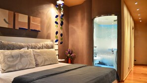 Una habitación de hotel moderna con una cama grande, cabina de ducha de vidrio y obras de arte colgadas en la pared.