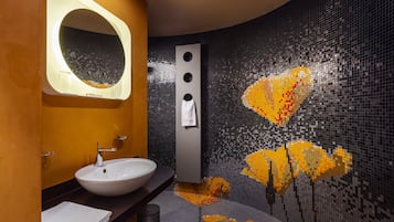 Bathroom features a unique mosaic tile design, a white sink, and a wall-mounted mirror.