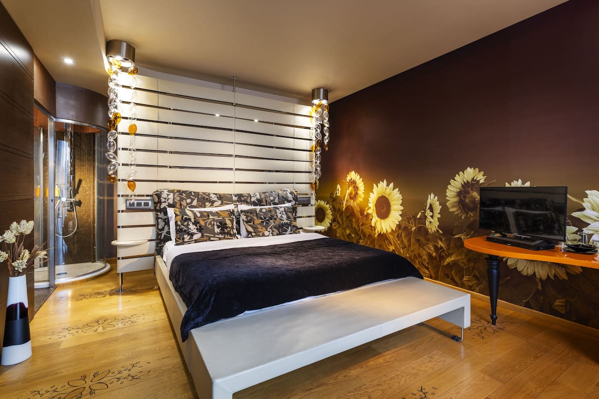 Un dormitorio moderno con una cama, un televisor y una pared decorada con estampado de girasoles.