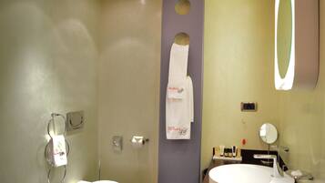 A bathroom with a toilet, sink, mirror, towel rack, and a towel hanging on the wall.