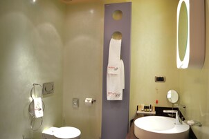 A bathroom with a toilet, sink, mirror, towel rack, and a towel hanging on the wall.