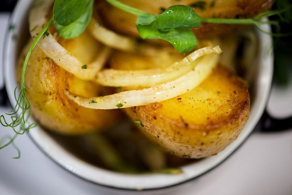 Un bol de patates rostides guarnides amb herbes.