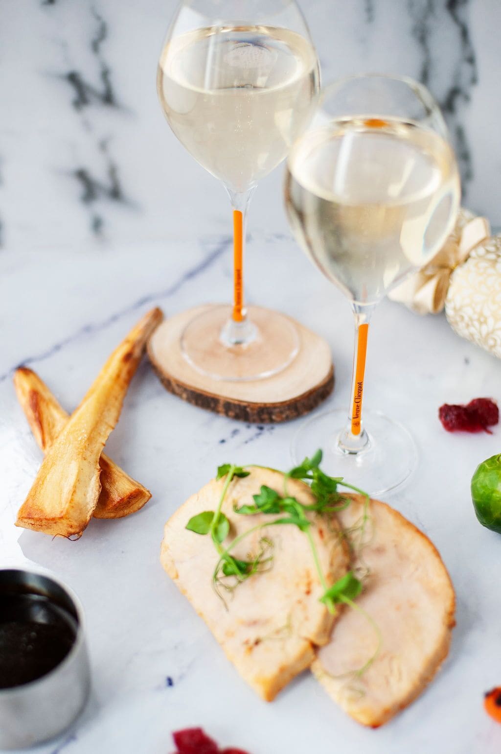 Two wine glasses on a marble surface with a slice of meat and a bone.