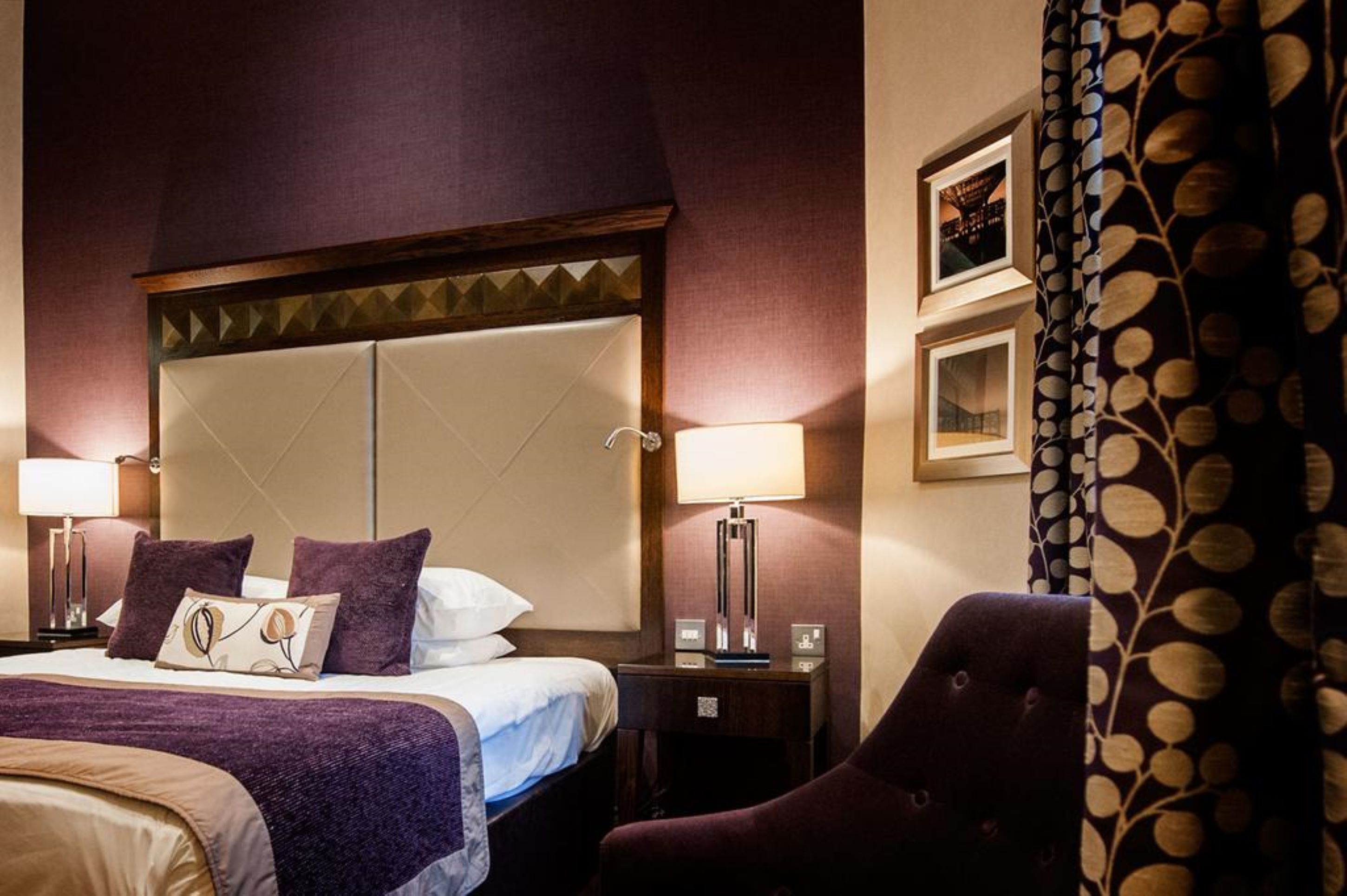 Una camera d'albergo con un letto grande, due lampade sui comodini, un comodino e una sedia.