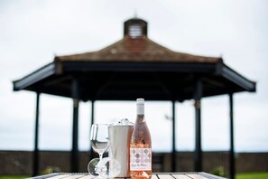 A gazebo with a metal roof and a brick base, a bottle of wine, and two glasses on a table. - Seamill Hydro Hotel & Resort (West Kilbride)