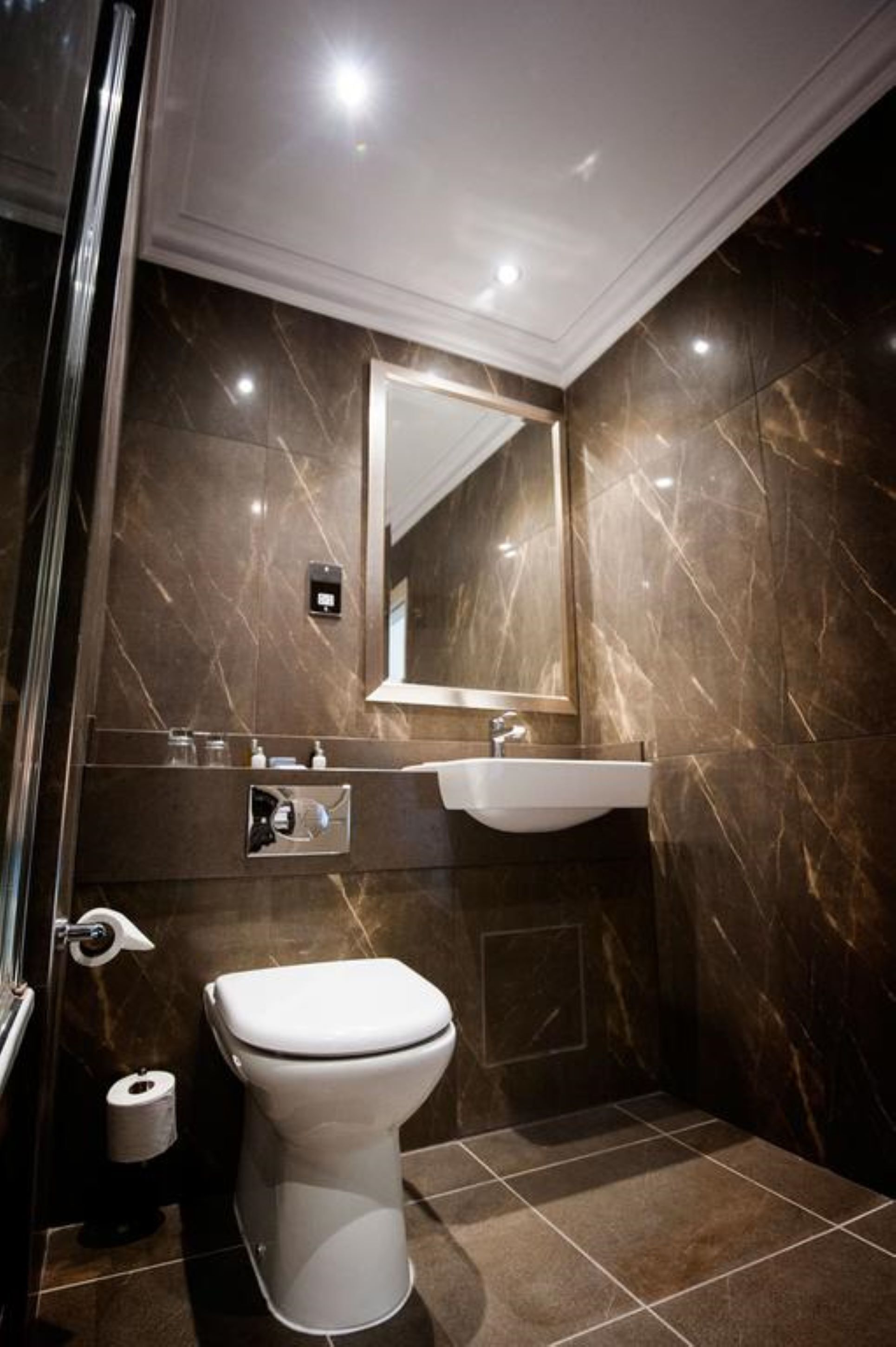 A modern bathroom with a toilet, sink, and mirror.