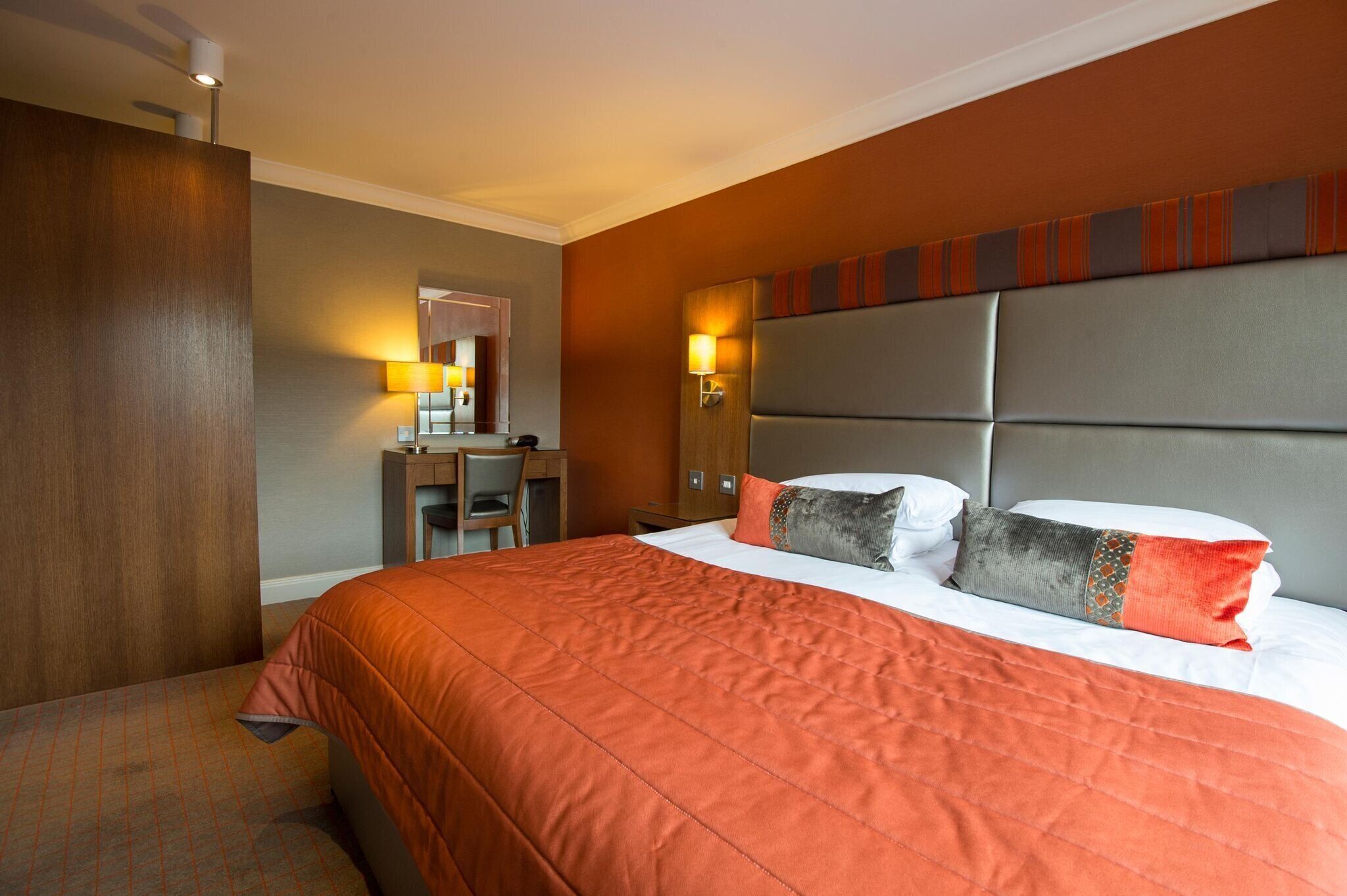 Une chambre d’hôtel avec un grand lit, un bureau et un miroir.