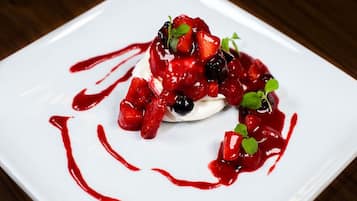 Un postre en un plato blanco con frutos rojos y salsa roja.