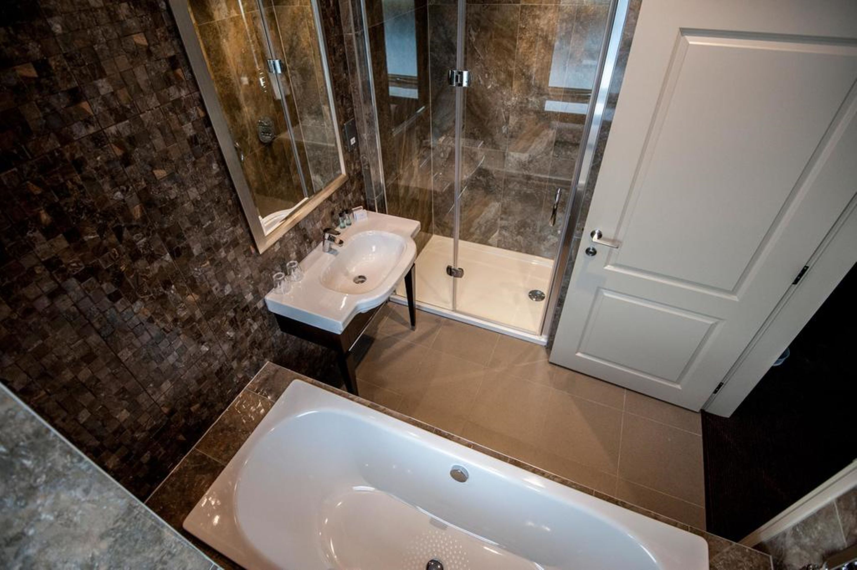 A modern bathroom with a glass-enclosed shower, a standalone bathtub, and a vanity with a sink.