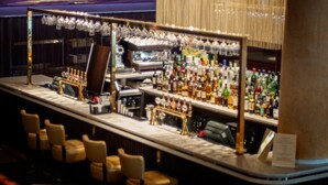 A bar area with a marble countertop, multiple bar stools, a variety of liquor bottles, and a large mirror reflecting the bar. - Seamill Hydro Hotel & Resort (West Kilbride)