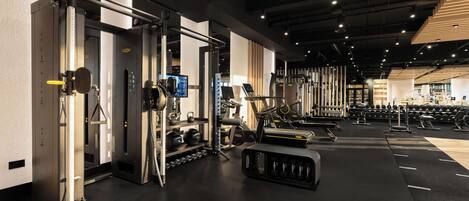 Un gimnasio moderno con varios equipos de ejercicio, incluyendo máquinas de pesas, cintas de correr y pesas libres.