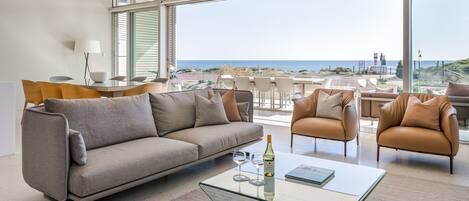 A modern living room with a sofa, armchairs, and a glass coffee table.