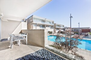 Un hotel moderno con piscina, mobiliario exterior y una vista despejada de la zona de la piscina.