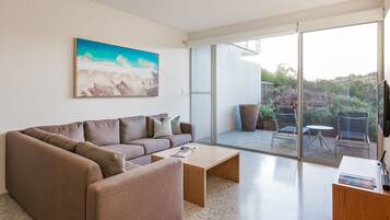A modern living room with a brown sofa, a coffee table, and a painting on the wall.