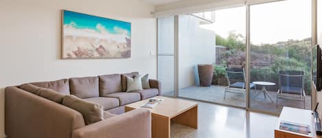 A modern living room with a brown sofa, a coffee table, and a painting on the wall.