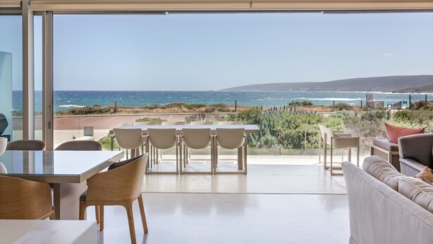 A modern interior with a large glass door leading to a balcony overlooking the ocean.