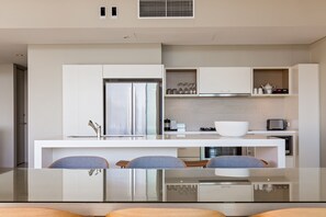 A modern kitchen with a central island, built-in appliances, and a seating area with chairs.