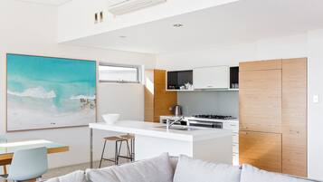 A modern kitchen with a central island, white cabinetry, and a large window.