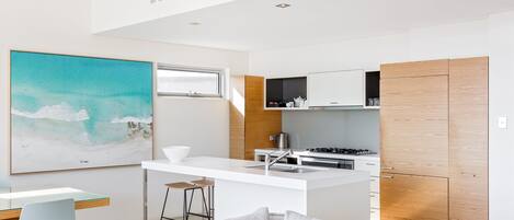 A modern kitchen with a central island, white cabinetry, and a large window.