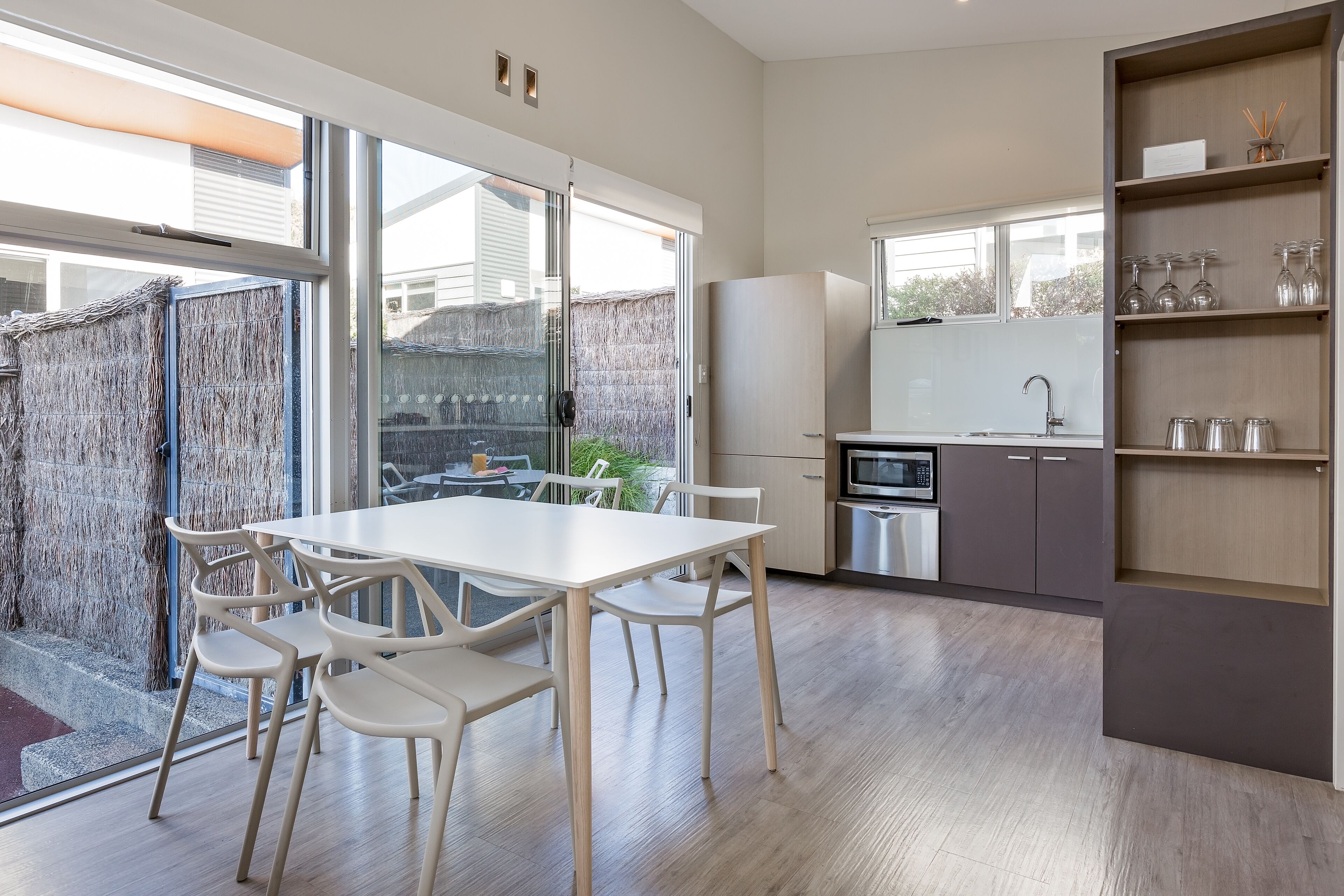 A modern kitchen with a dining area, large windows, and a view of the backyard.