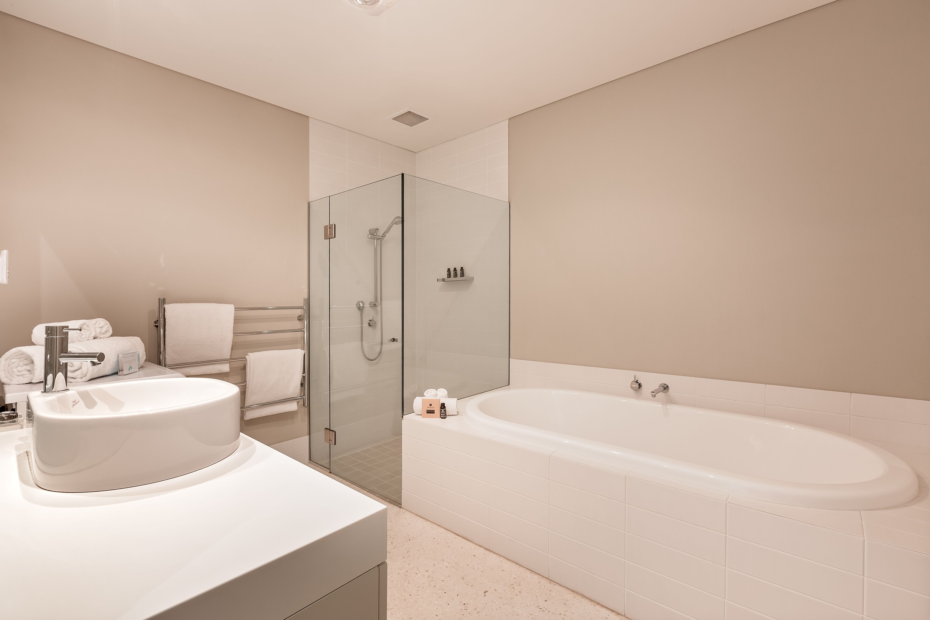 A modern bathroom with a large sink, a bathtub, and a glass-enclosed shower.