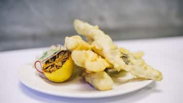 A plate with tempura, lemon, and a small salad.