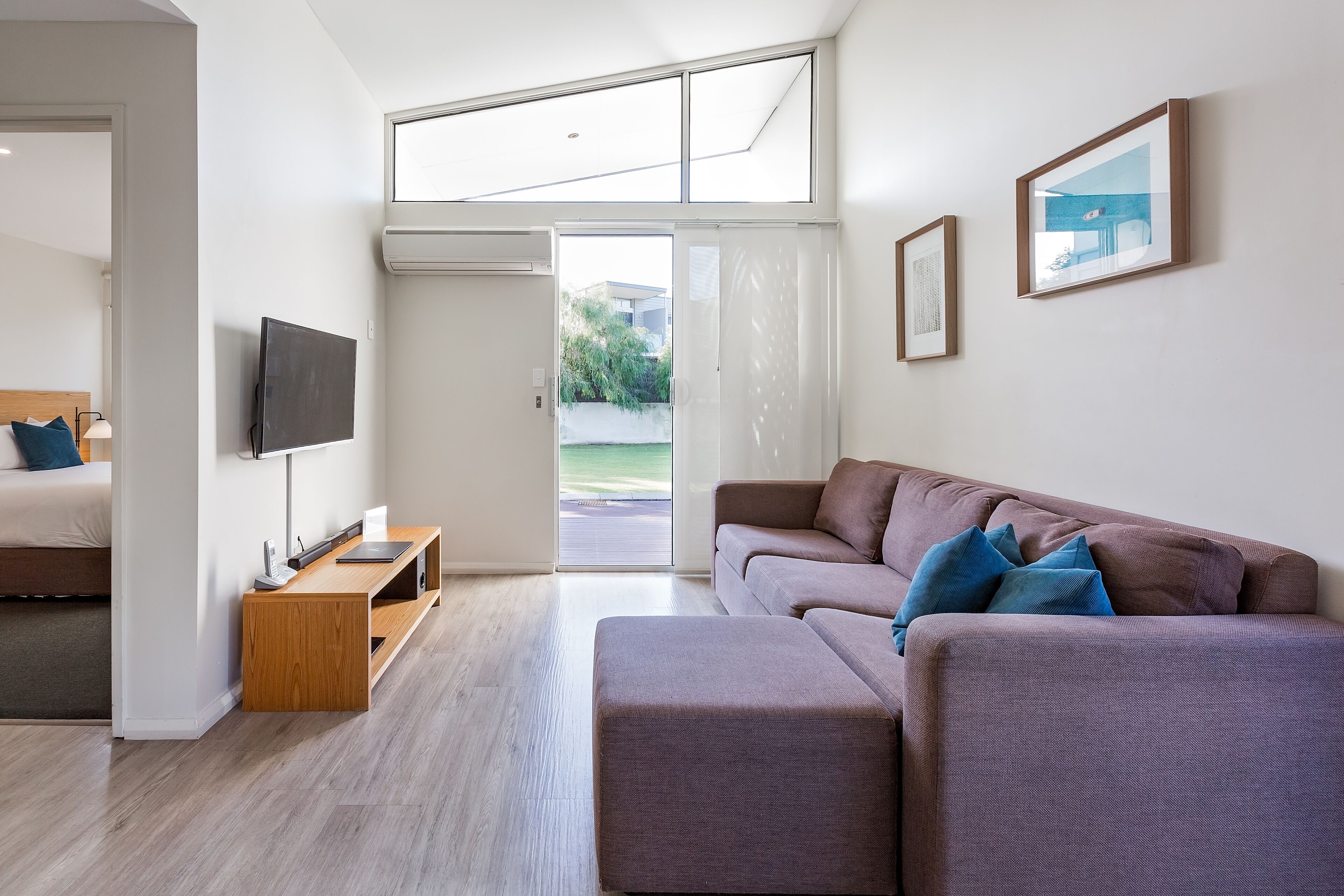 A modern living room with a sofa, a TV, and a wooden side table.