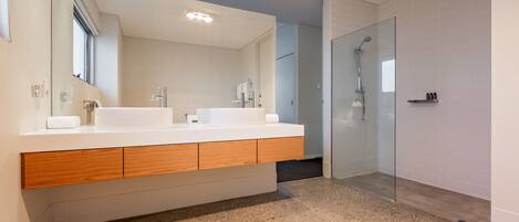 A modern bathroom with a double sink vanity, a glass shower enclosure, and a speckled floor.