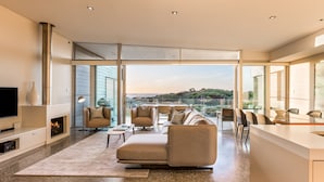 A modern living room with a fireplace, comfortable seating, and large windows offering a view of the outdoors.