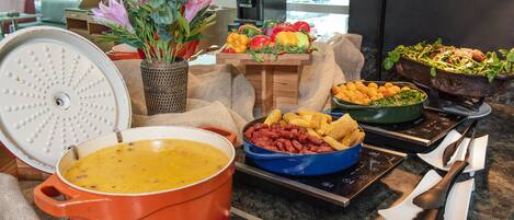 Una encimera de cocina con una olla de sopa, un tazón de frijoles, una bandeja de papas fritas y una variedad de verduras.