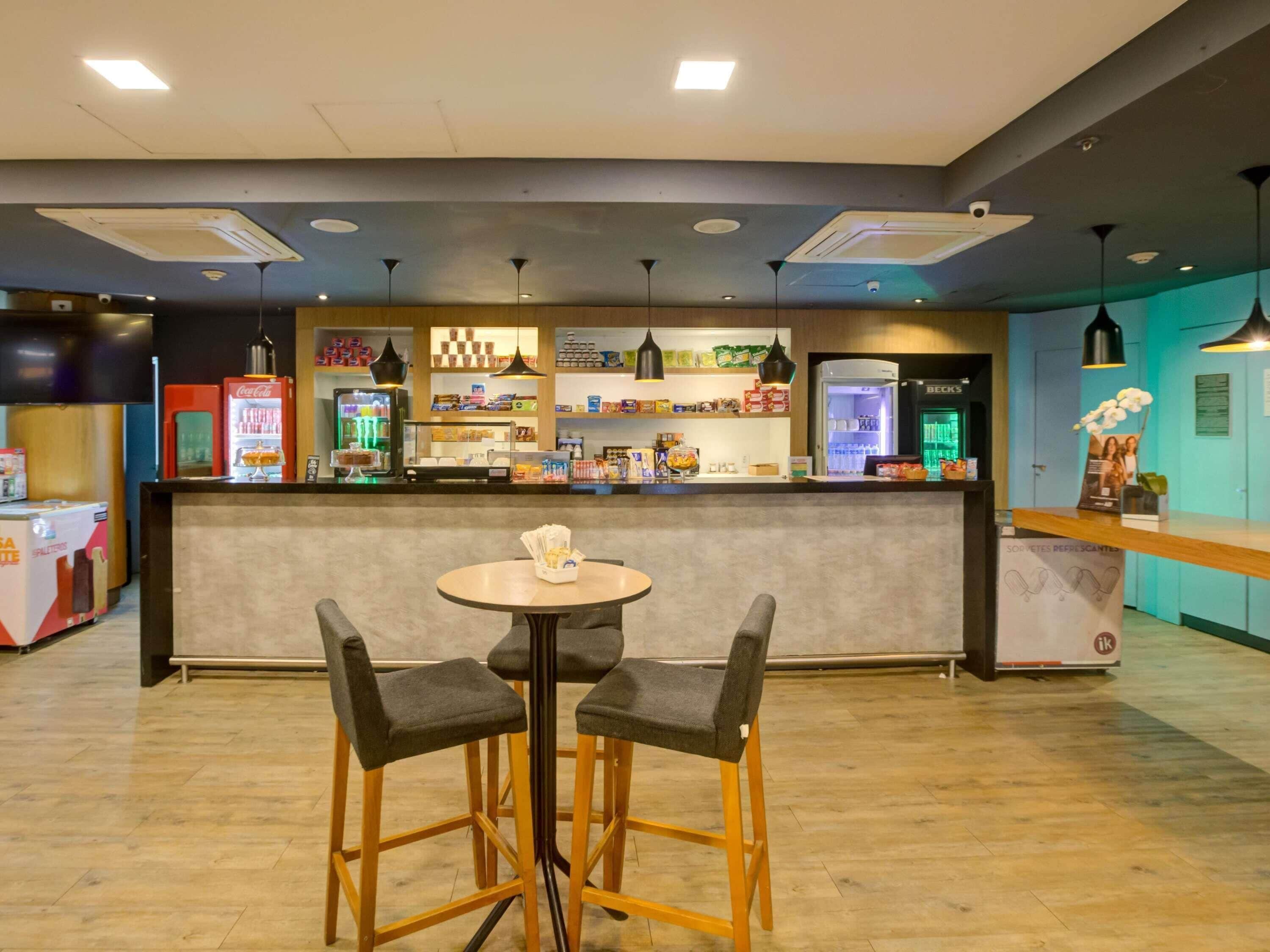 Uma área de bar moderna, com balcão, dois bancos e uma mesa.